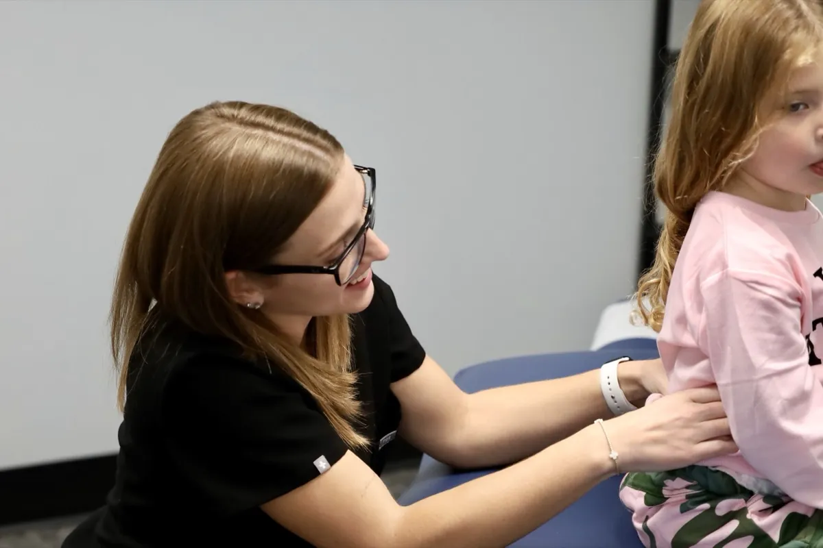 Tulsa pediatric chiropractor talking with a young patient during a first visit exam