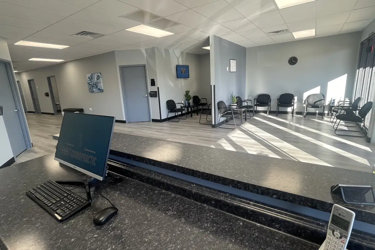 View from the front desk of the Frost Chiropractic waiting room in Tulsa, with a monitor and phone on the counter