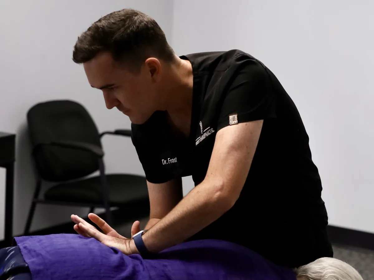 Dr. Hyatt Frost with his hands on the back of a patient lying face down at Frost Chiropractic in Tulsa