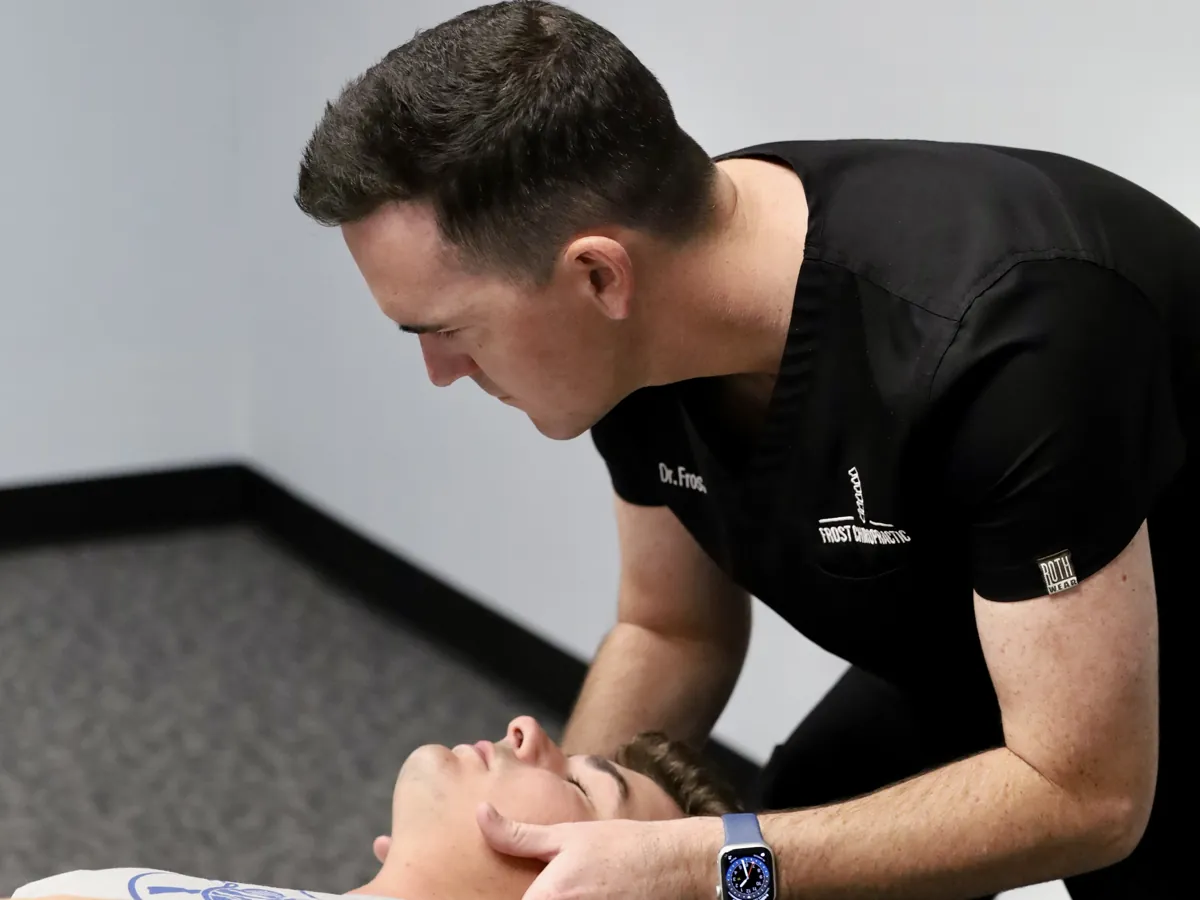 Dr. Hyatt Frost cradling a patient's head and neck on the adjusting table at Frost Chiropractic in Tulsa