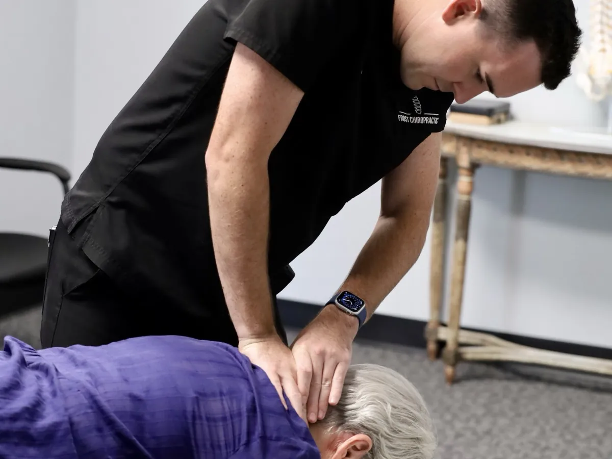 Dr. Hyatt Frost with his hands at the neck and upper back of a patient lying face down at Frost Chiropractic in Tulsa